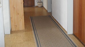 A hallway with a wooden door at the end, a small wooden cabinet, a potted plant, and a mirror on the wall. - A place in the sun in the Black Forest, for hiking, relaxing and enjoying (Ühlingen- Birkendorf)