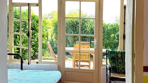 A room with a bed, a ceiling fan, a window with a view of a garden, and a chair. - Restored holiday house with all comforts near the sea (Magescq)