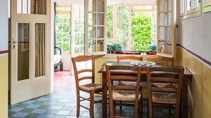 A dining area with a checkered floor, wooden chairs, a table, and a hanging light fixture. - Restored holiday house with all comforts near the sea (Magescq)