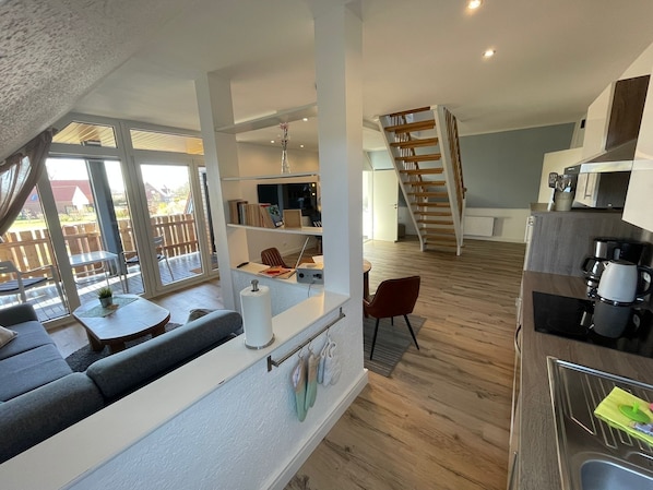 Ein modernes Interieur mit Sofa, Esstisch, Küchenzeile und einer Treppe.