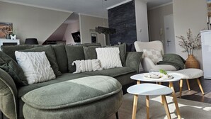 Ein modernes Wohnzimmer mit einer Eckcouch, einem runden Couchtisch und einem Essbereich.