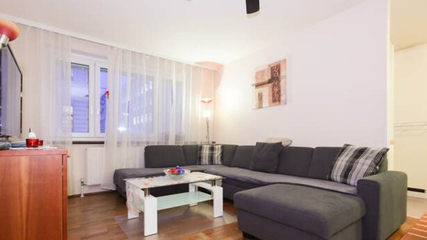 Een moderne woonkamer met een grijze modulaire bank, een witte salontafel en een houten vloer.