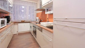 Een kleine keuken met een magnetron, oven en vaatwasser.