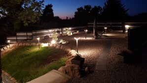 A well-lit outdoor patio area with a gravel path, seating arrangements, and a decorative sculpture. - Weissenhäuser Strand Ostsee Holiday house with high equipment (Wangels)
