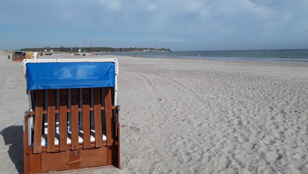 A beach with a wooden chair covered with a blue tarp, a sandy beach, and a calm sea. - Weissenhäuser Strand Ostsee Holiday house with high equipment (Wangels)