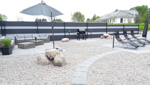 A patio area with outdoor furniture, a barbecue grill, and a decorative rock arrangement. - Weissenhäuser Strand Ostsee Holiday house with high equipment (Wangels)