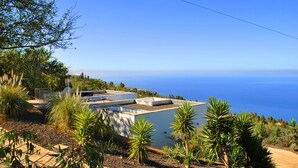 A modern building with a flat roof, surrounded by a variety of plants and trees, overlooking a body of water. - HOLIDAYS WITH VISION AND --RUHIG ENTSPANNEND-- COMFORTABLE AND QUALITY  (Tijarafe)