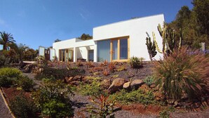 A modern white building with large windows and a desert garden with cacti and other plants. - HOLIDAYS WITH VISION AND --RUHIG ENTSPANNEND-- COMFORTABLE AND QUALITY  (Tijarafe)