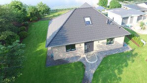 Una casa moderna con techo inclinado, un pequeño porche y un césped bien cuidado.