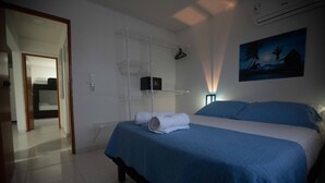 Une chambre à coucher comprenant un lit, une table de chevet, une étagère fixée au mur et un tableau.