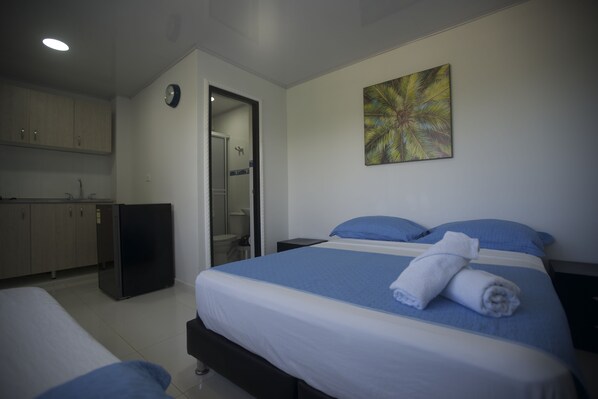 A hotel room with a bed, a small desk, a mirror, a wardrobe, and a bathroom visible through an open door. - Chalet Del Mar (San Andrés)