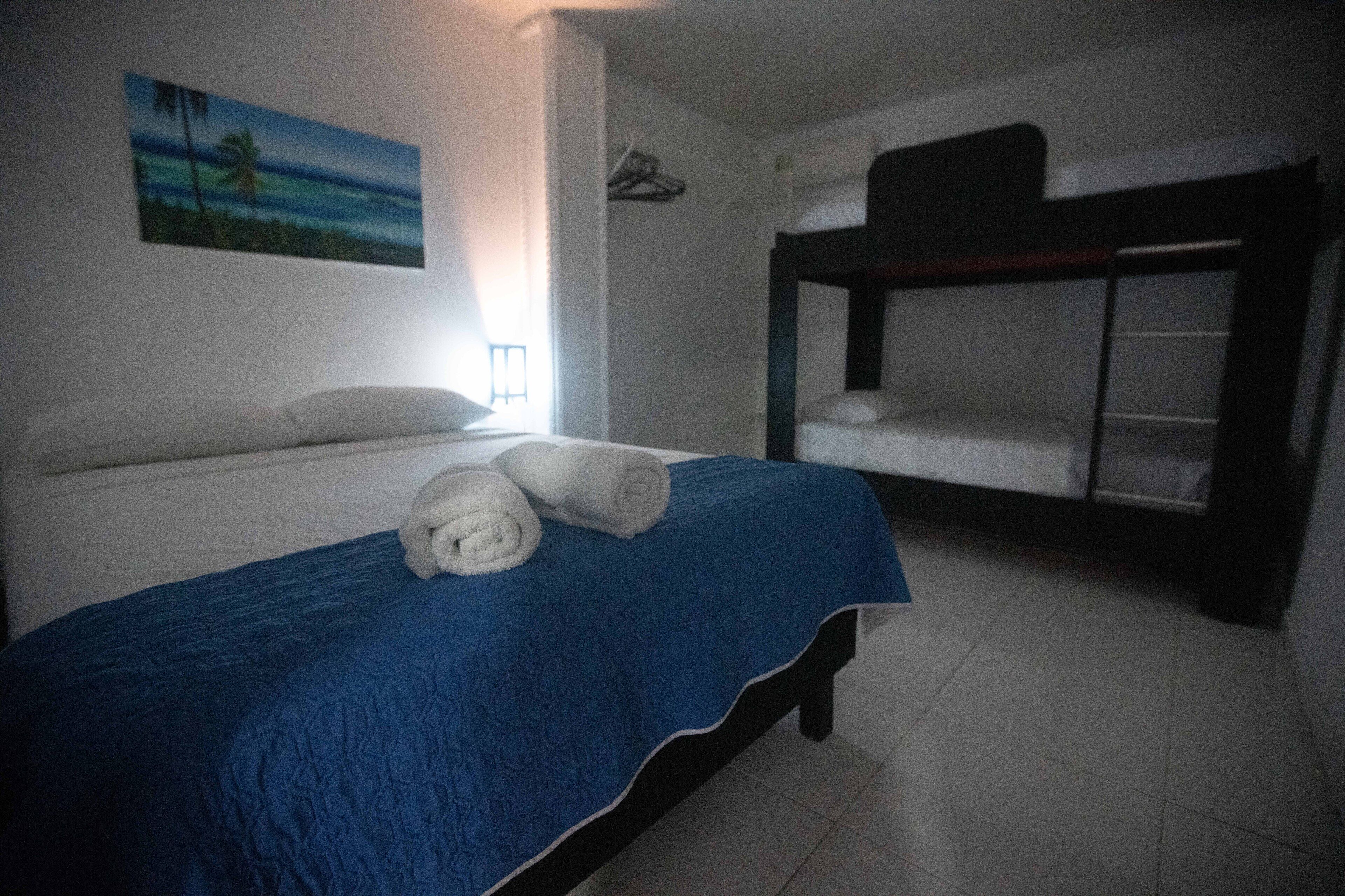 Une chambre avec un lit, un lit superposé et un tableau représentant une scène de plage.