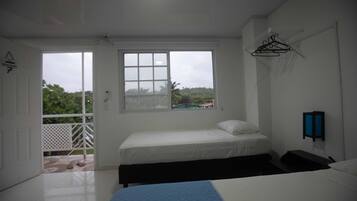 Un dormitorio con cama, ventana, puerta y un perchero en la pared.