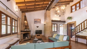 Un salon chaleureux avec une cheminée, un téléviseur et un escalier en bois.