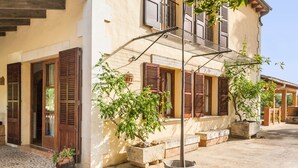 Un bâtiment avec une entrée carrelée, des volets en bois et des plantes en pot.