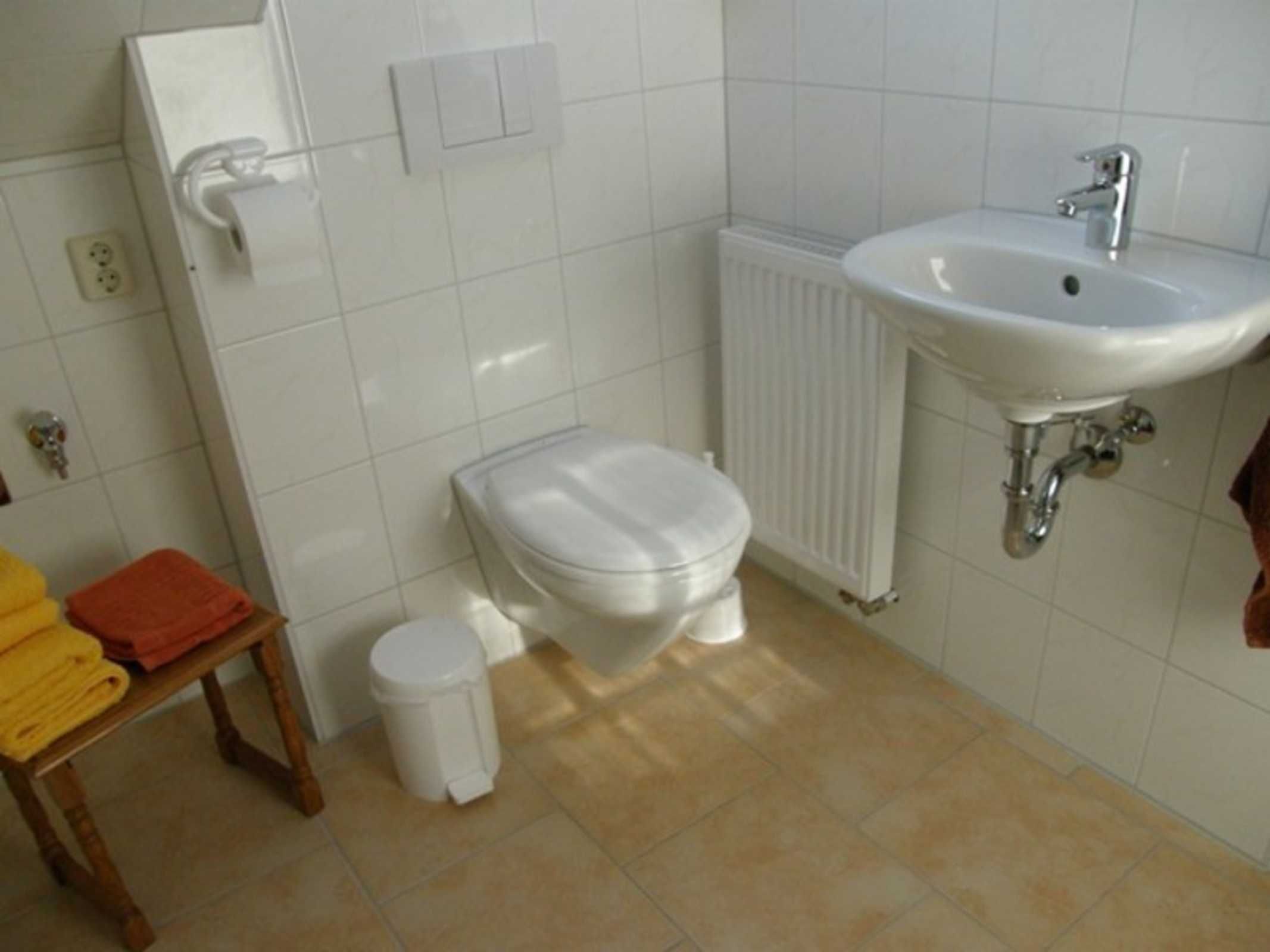 Ein Badezimmer mit Toilette, Waschbecken und einer kleinen Mülleimer.