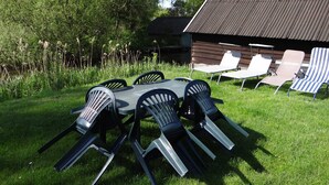Un patio con tavolo e sedie, immerso nel verde prato e alberi.