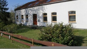 Un edificio bianco con tetto in tegole, una porta in legno e diverse finestre.