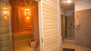 A sauna with wooden walls and a bench, a glass shower enclosure, and a towel rack. - Luxury wellness villa in a quiet area of Northern Istria (Lanišće)