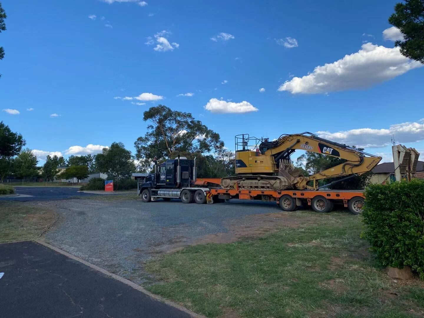 A construction vehicle on a trailer parked on a road.