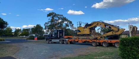 A construction vehicle on a trailer parked on a road.