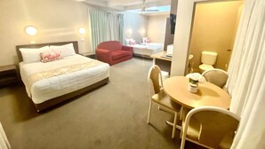 A hotel room with a large bed, a desk with a chair, a small table with a chair, and a separate seating area with a couch and chairs. - Apollo Motel Parkes (Parkes)