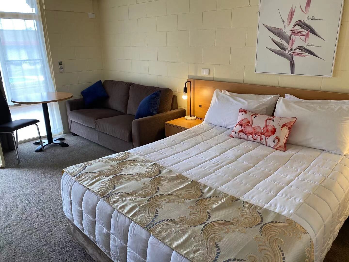 Una habitación de hotel con una cama grande, un sofá, una mesita y una lámpara.