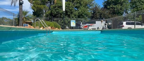 Una piscina al aire libre de temporada, sombrillas