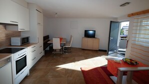 Una cocina moderna con armarios blancos, un microondas, un horno y un comedor con mesa y sillas.