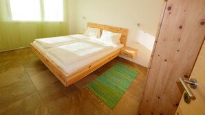 Un dormitorio con una cama de madera, una mesita de noche, un tapete verde a rayas y un armario de madera.