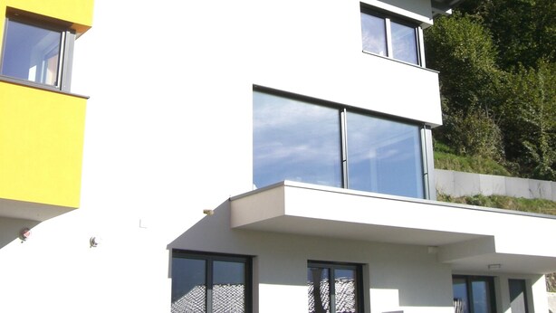 Un edificio moderno de dos pisos con techo plano y ventanas grandes.