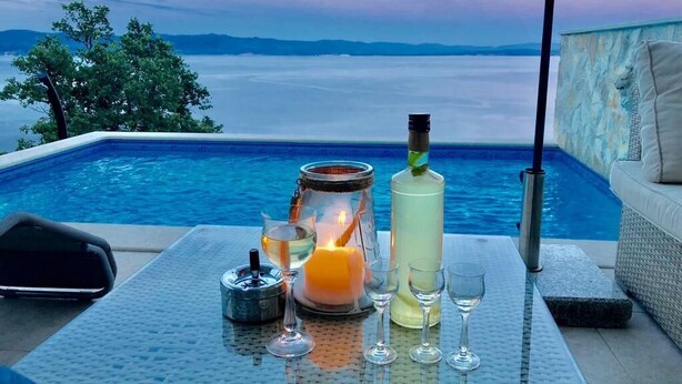 A poolside setting with a table set for two, featuring a candle, a bottle, and glasses. - Private hillside location ★★★★ with special views, ideal for couples (Medveja)