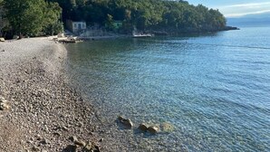 A pebble beach with clear water, a small building, and a forested hillside. - Private hillside location ★★★★ with special views, ideal for couples (Medveja)