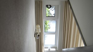 Een trap met een houten leuning, een raam met een krans en een wandlamp.