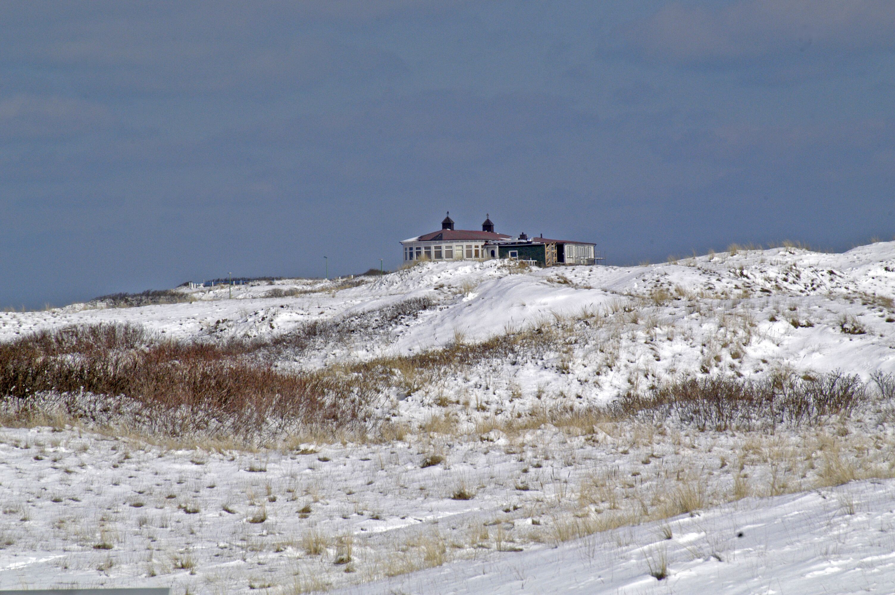A snow-covered landscape with a house on a hill.