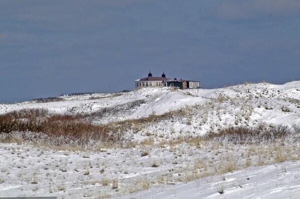 A snow-covered landscape with a house on a hill. - Langeoog: Cozy vacation home with sun terrace (Langeoog)