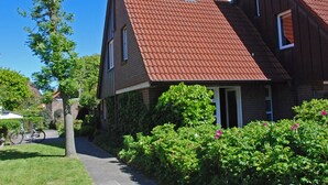 Een tweelaags huis met een rode dakbedekking van tegels, een bakstenen gevel en een duidelijke voordeur.