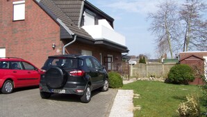 A two-story house with a brick facade, a driveway, and a garden. - Peaceful well furnished apartment near the North Sea spa Büsum (Westerdeichstrich)