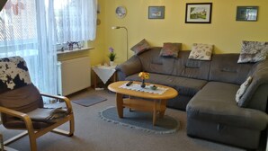 A living room with a brown sofa, a wooden chair, a small coffee table, and a radiator. - Peaceful well furnished apartment near the North Sea spa Büsum (Westerdeichstrich)