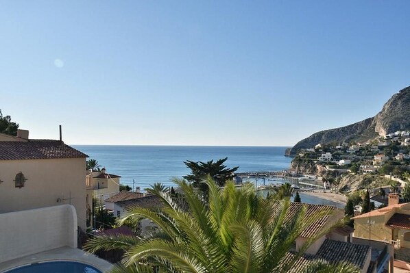 A coastal town with buildings, a clear sky, and a view of the sea.