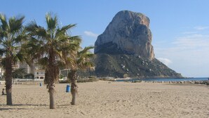 A sandy beach with palm trees and a large rock formation in the background. - Peaceful Villa with heavenly sea view and panoramic view (Calp)