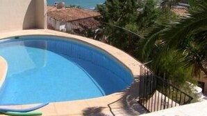 A swimming pool with a curved edge, surrounded by a low fence and palm trees. - Peaceful Villa with heavenly sea view and panoramic view (Calp)