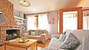 A cozy living room with a fireplace, a sofa, a coffee table, and a bookshelf.