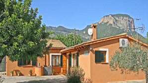 A Mediterranean-style building with a tiled roof, a satellite dish, and a mountain backdrop.