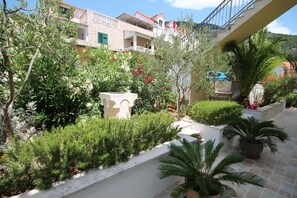 Escape to a tranquil courtyard surrounded by lush greenery and a stone bench for a peaceful retreat.