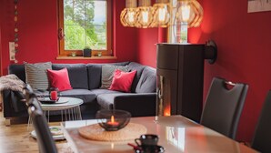 Una sala moderna con un sofá gris, cojines rojos, una mesa de centro redonda y un mueble negro.