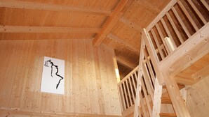 Un interior de madera con una escalera y una pizarra con un dibujo en negro.