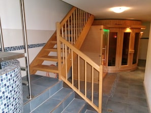Eine Holztreppe mit einer Glastür, die zu einem Raum mit Fliesenboden führt.