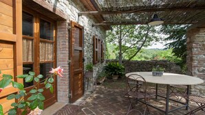 An outdoor patio with a round table and chairs, surrounded by stone walls and potted plants. - Beautiful accommodation in a quiet location and with a huge garden,Wi-Fi,t5 (Pomaia)