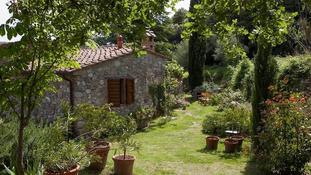 A stone house with a tiled roof, surrounded by a well-maintained garden with various potted plants and a grassy path. - Beautiful accommodation in a quiet location and with a huge garden,Wi-Fi,t5 (Pomaia)
